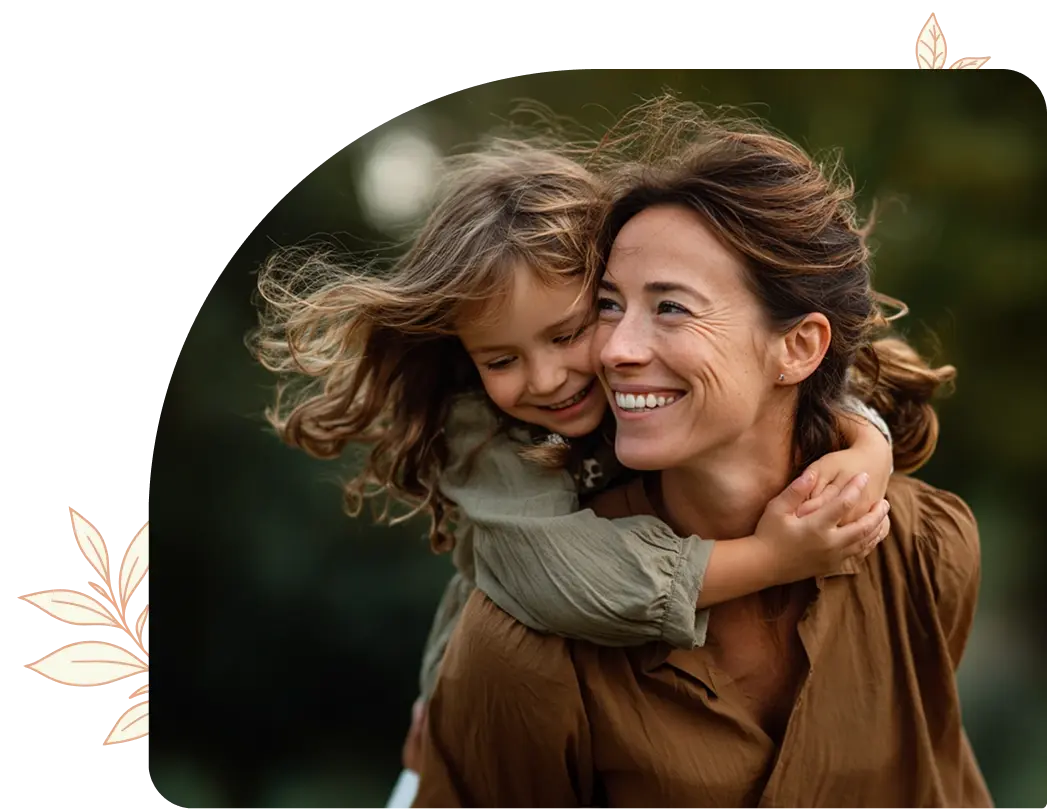 A mother smiling and embracing her child outdoors